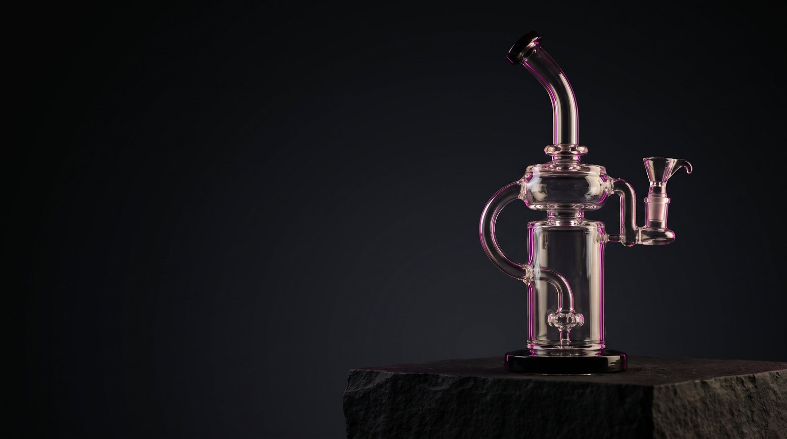 Hand-blown glass percolator piece lit in magenta on a black stone plinth